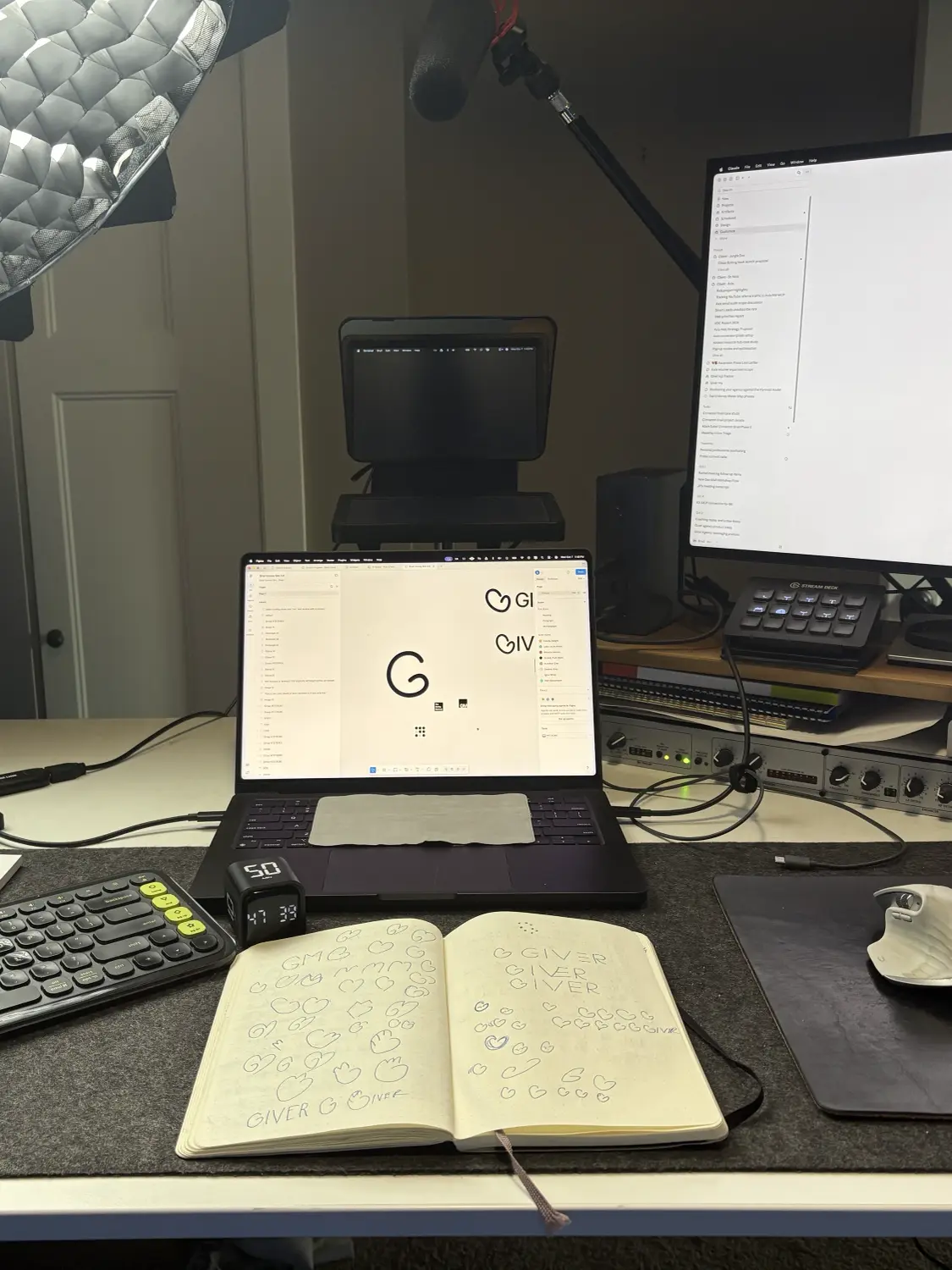 The Giver mark in Figma on my laptop, with logo sketches in a notebook in front of it