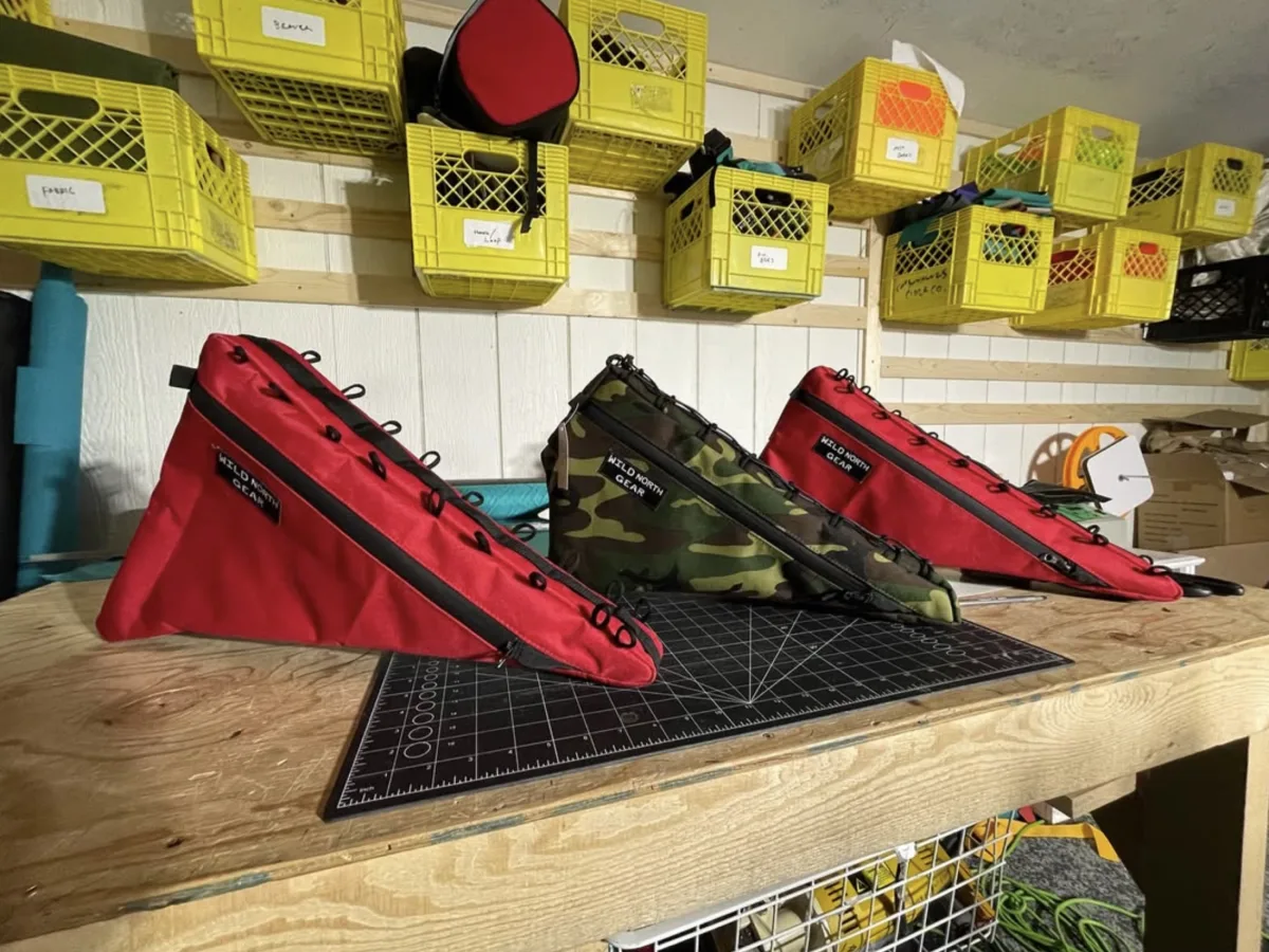 Three frame bags in red and camo on a cutting mat in the workshop